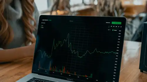 A laptop on a table showing a falling price chart